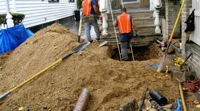 Contractors performing foundation protection and exterior drainage excavation near residential home steps in Detroit, MI